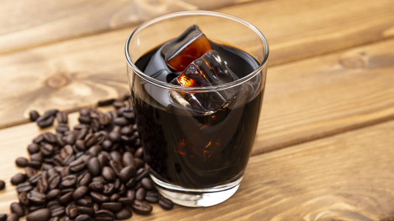 Glass of cold brew next to coffee beans