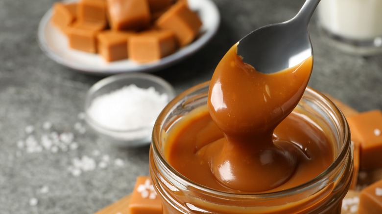 spooning caramel sauce out of a jar