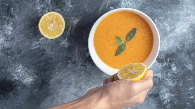 squeezing lemon into soup bowl