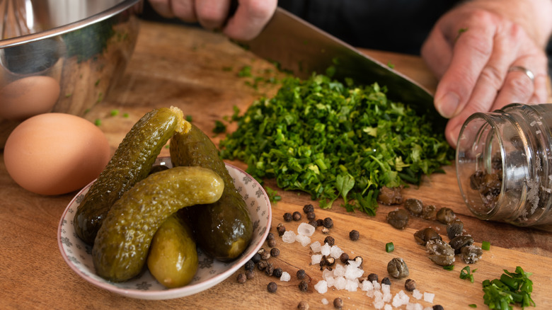 chopping ingredients for sauce gribiche on cutting board