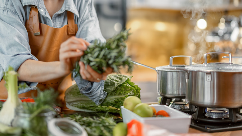 Person cooking with herbs and vegetables