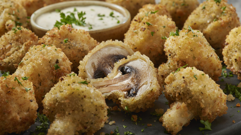 plate of breaded and fried mushrooms next to ranch dipping sauce