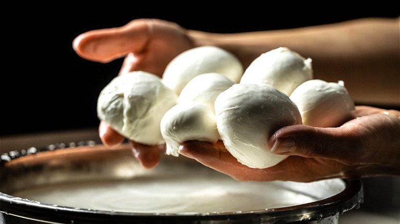 Balls of fresh mozzarella in hands 