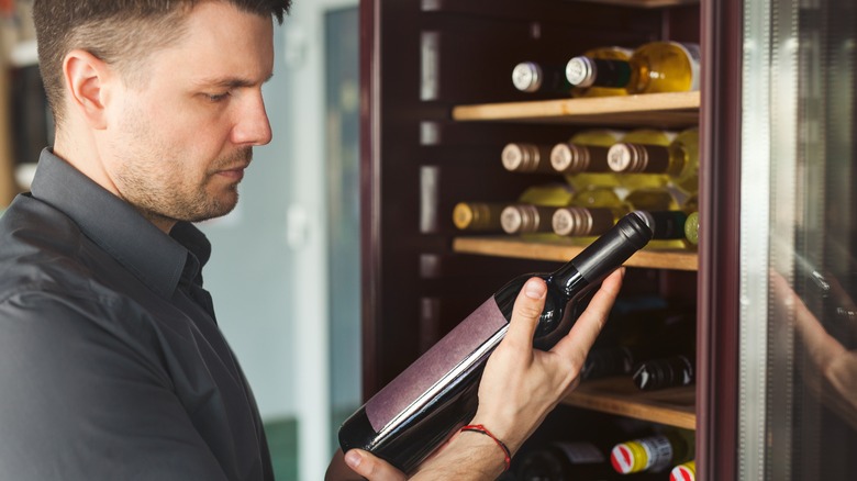 man looking at wine bottle