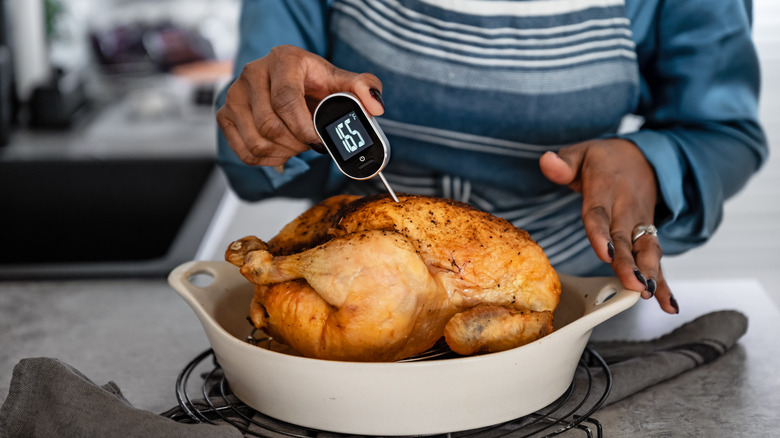 woman placing a thermometer into turkey