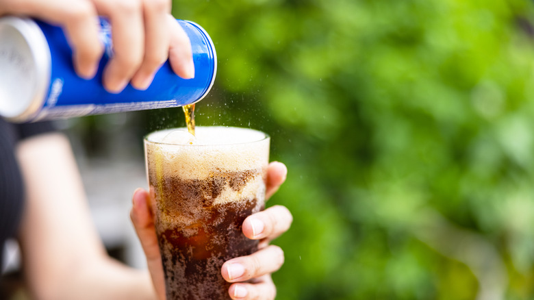 pouring canned cola into cup