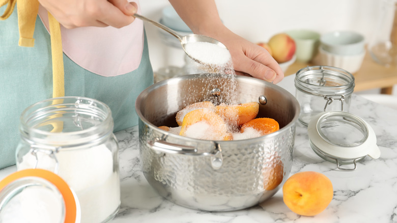 Cook adding sugar to apricots