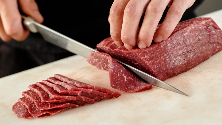 Person thinly slicing meat