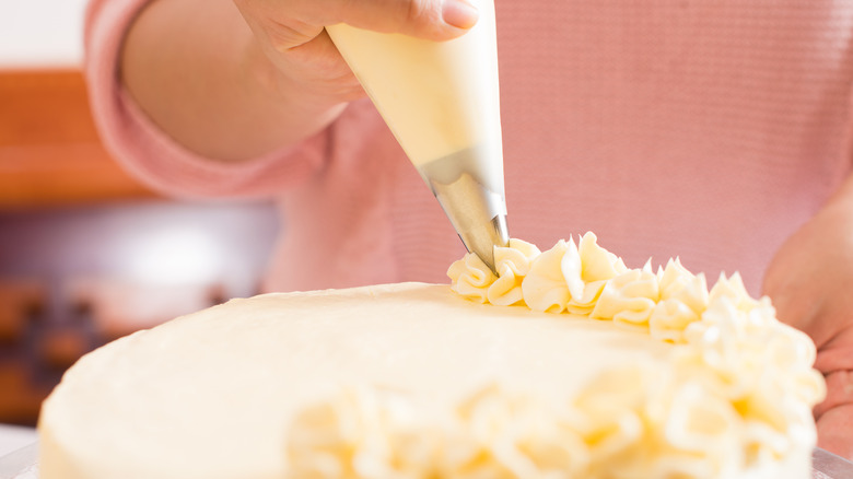 Piping frosting onto cake