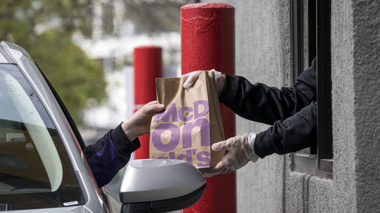 handing a McDonald's bag to customer at drive thru