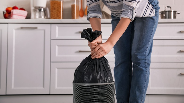 person pulling trash bag out