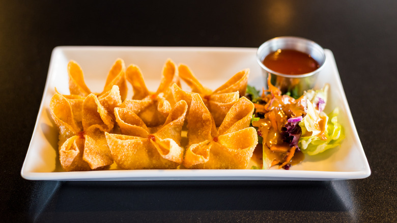 Crab rangoon on plate with salad and dipping sauce