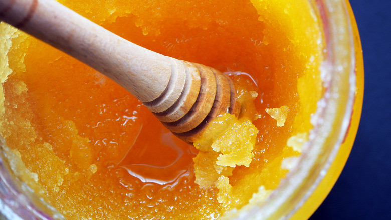 close-up open glass jar of crystallized honey