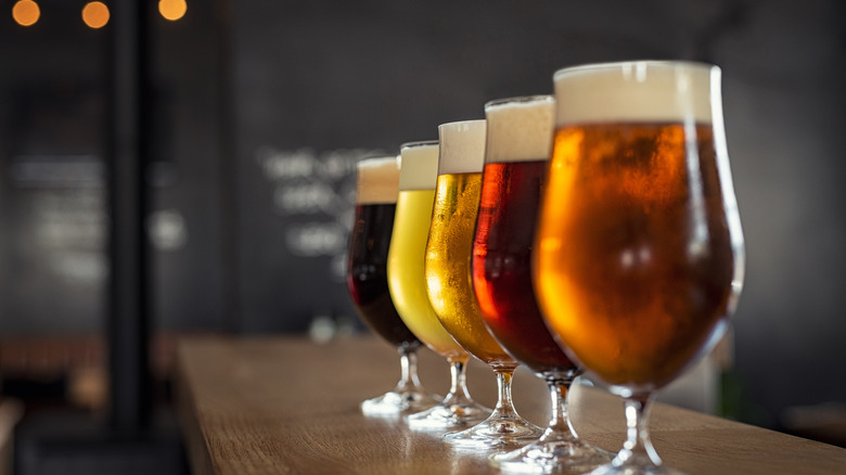 Different colors of beer lined up on bar