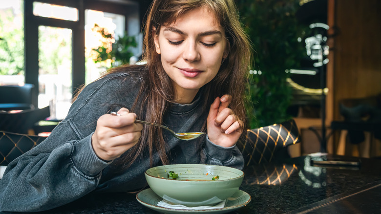 Woman eating bowl of soup