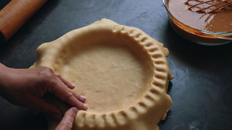 person preparing and crimping pie crust