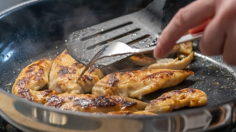 person searing chicken in skillet