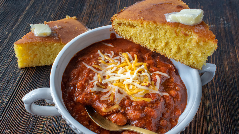 a bowl of hearty chili with two big slices of homemade cornbread on the side