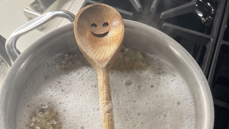 smiley face wooden spoon on top of a boiling pot