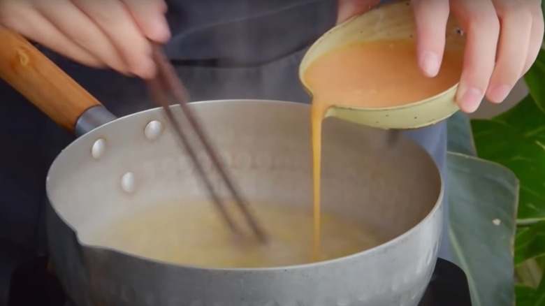 pouring egg into soup