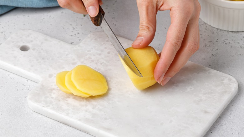 Person slicing a potato