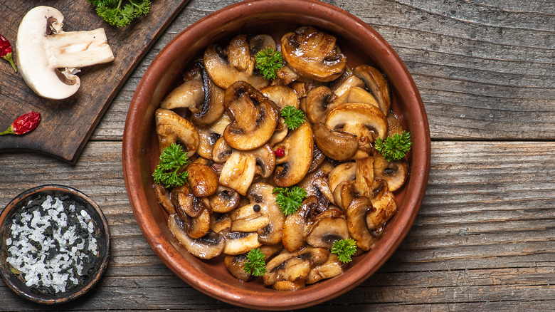 Roasted mushrooms in a bowl on wood surface