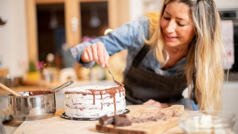 applying chocolate drizzle to cake