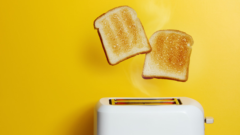 Two slices of bread popping out of white toaster