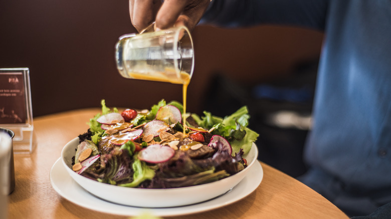 Pouring dressing onto salad