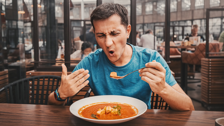 Man eating a spicy meal and grimacing