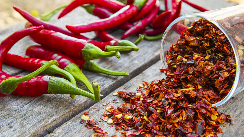 Chile peppers and red pepper flakes on a wooden table