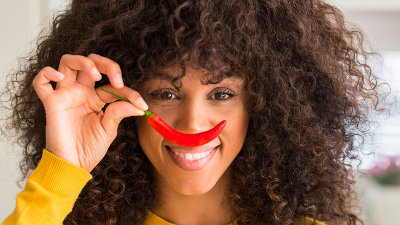 Woman holding a red hot chile pepper in front of her face