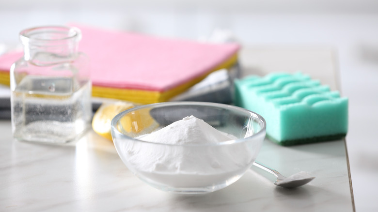 dish of baking soda on table with other cleaning supplies