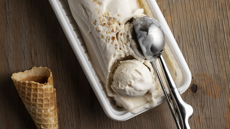 Ice cream in a container with scoop and waffle cone