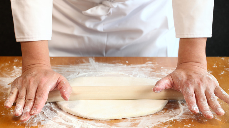 Chef rolling out dough on board