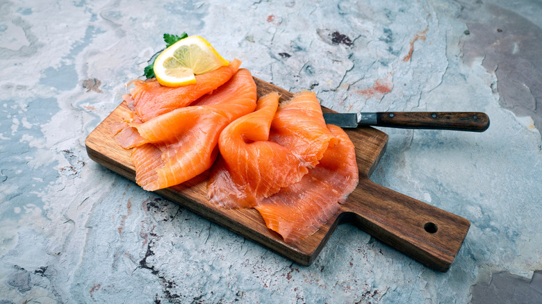 Smoked salmon with lemon slice a wooden chopping board.