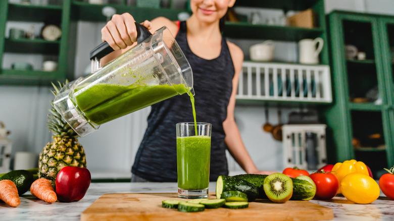 pouring green smoothie into glass