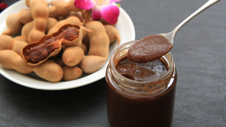 jar of tamarind paste in front of bowl filled with tamarind