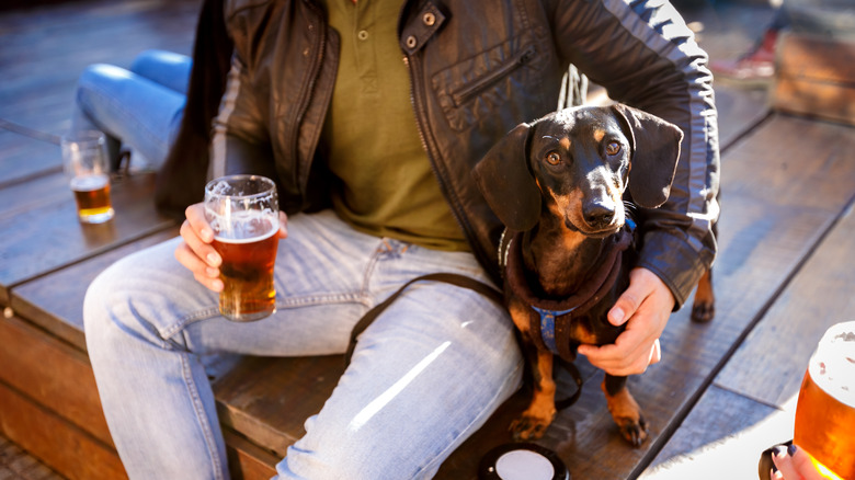 A man holds a beer beside his dog