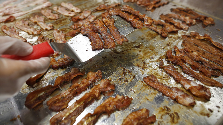 person flipping bacon on grill