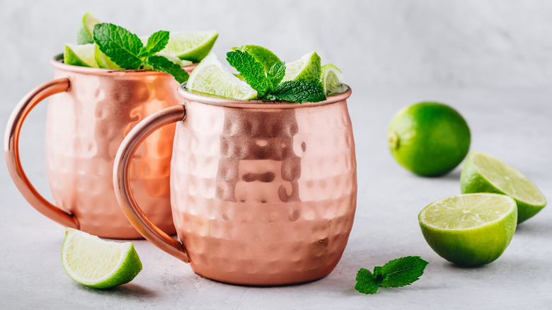 Two copper mugs garnished with mint and lime