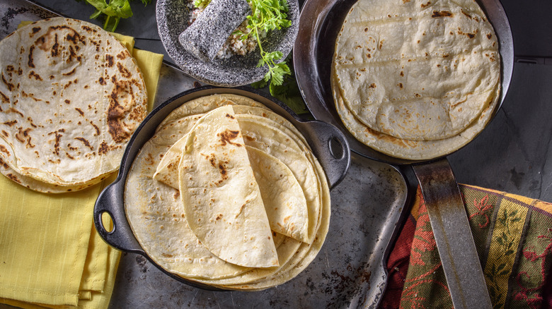 three stacks of cooked tortillas next to molcajete