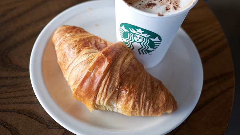 Starbucks croissant on a plate next to a drink