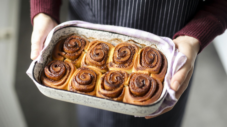 Person holding pan of cinnamon rolls