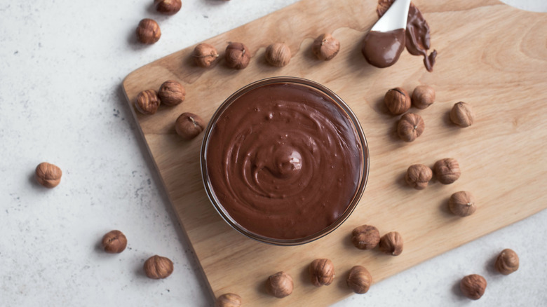 Nutella surrounded by hazelnuts 