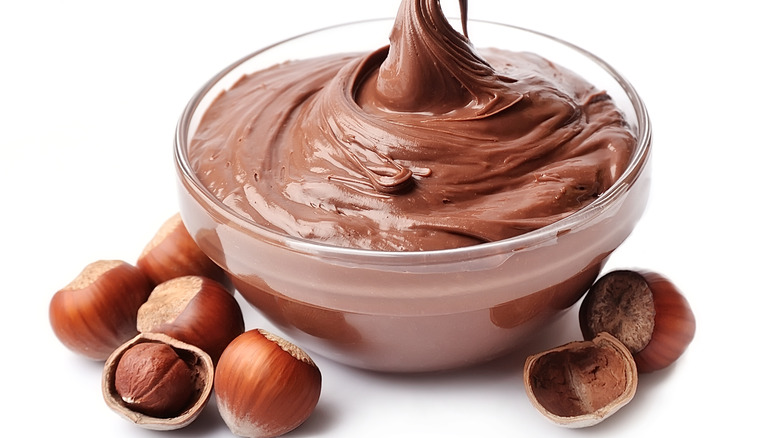 Nutella spread surrounded by hazelnuts 