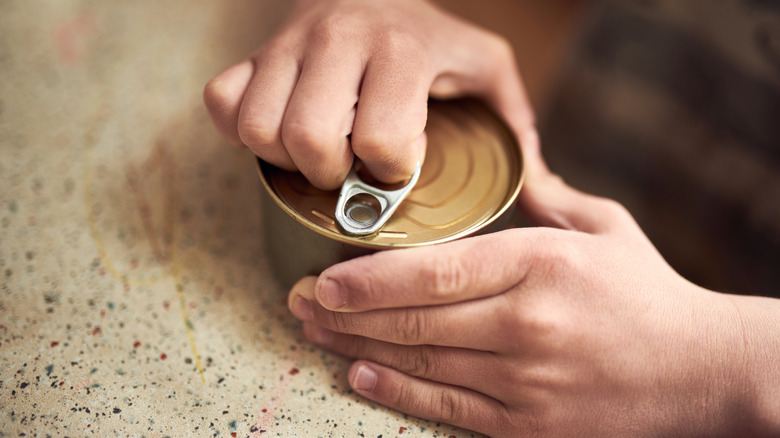 person opening can of tuna