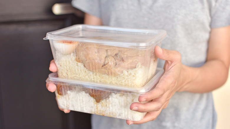 Woman carrying stacks of tupperware with food