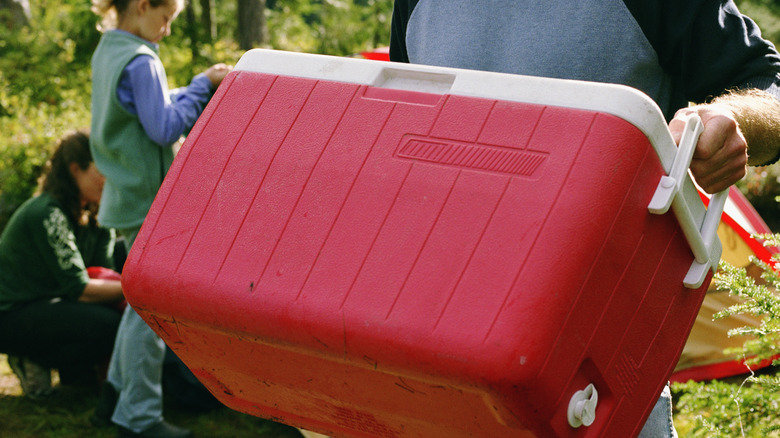 Man carrying a red cooler