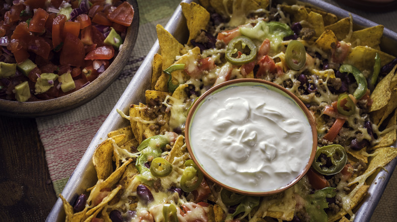 Tray of nachos with sour cream in the center